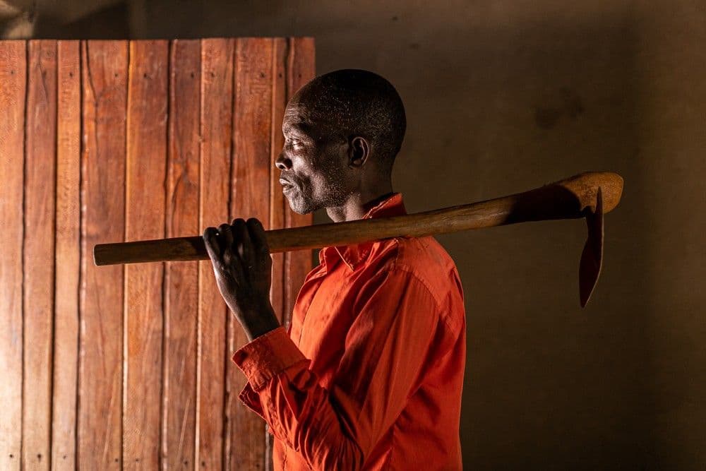 A man holding a hoe staring at the open door